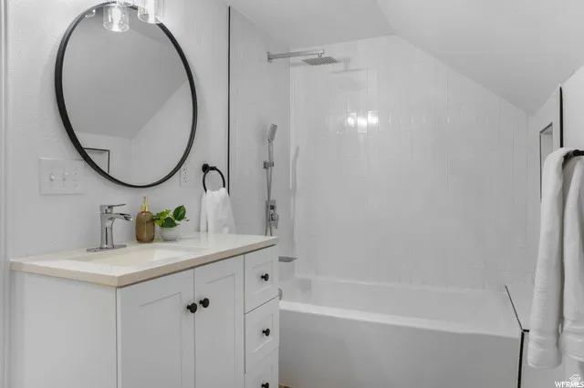 Full bath with vanity, lofted ceiling, and tub / shower combination