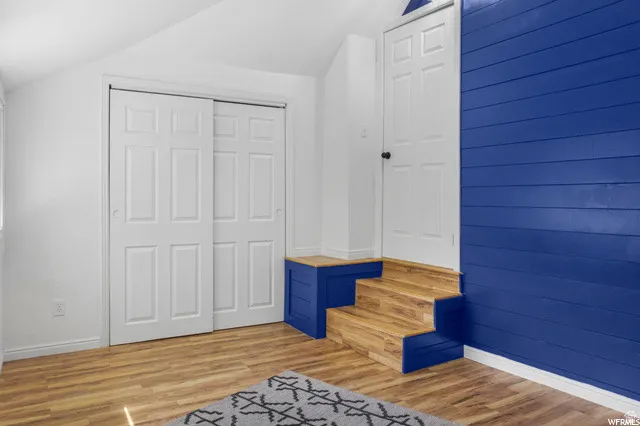 Unfurnished bedroom with light wood finished floors, vaulted ceiling, and a closet