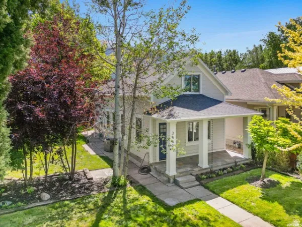 View of front of property featuring a front lawn, a shingled roof, and covered porch