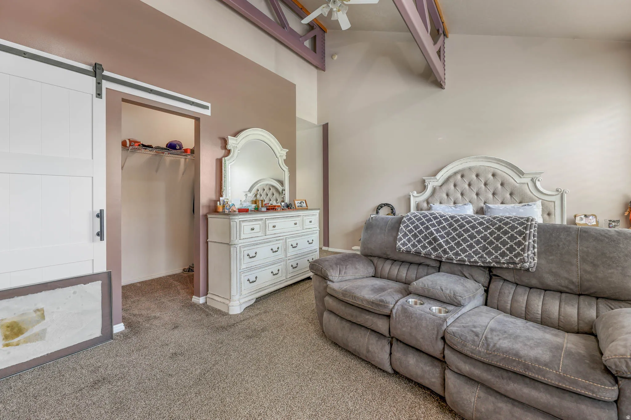 Carpeted bedroom with a barn door, a walk in closet, and a high ceiling