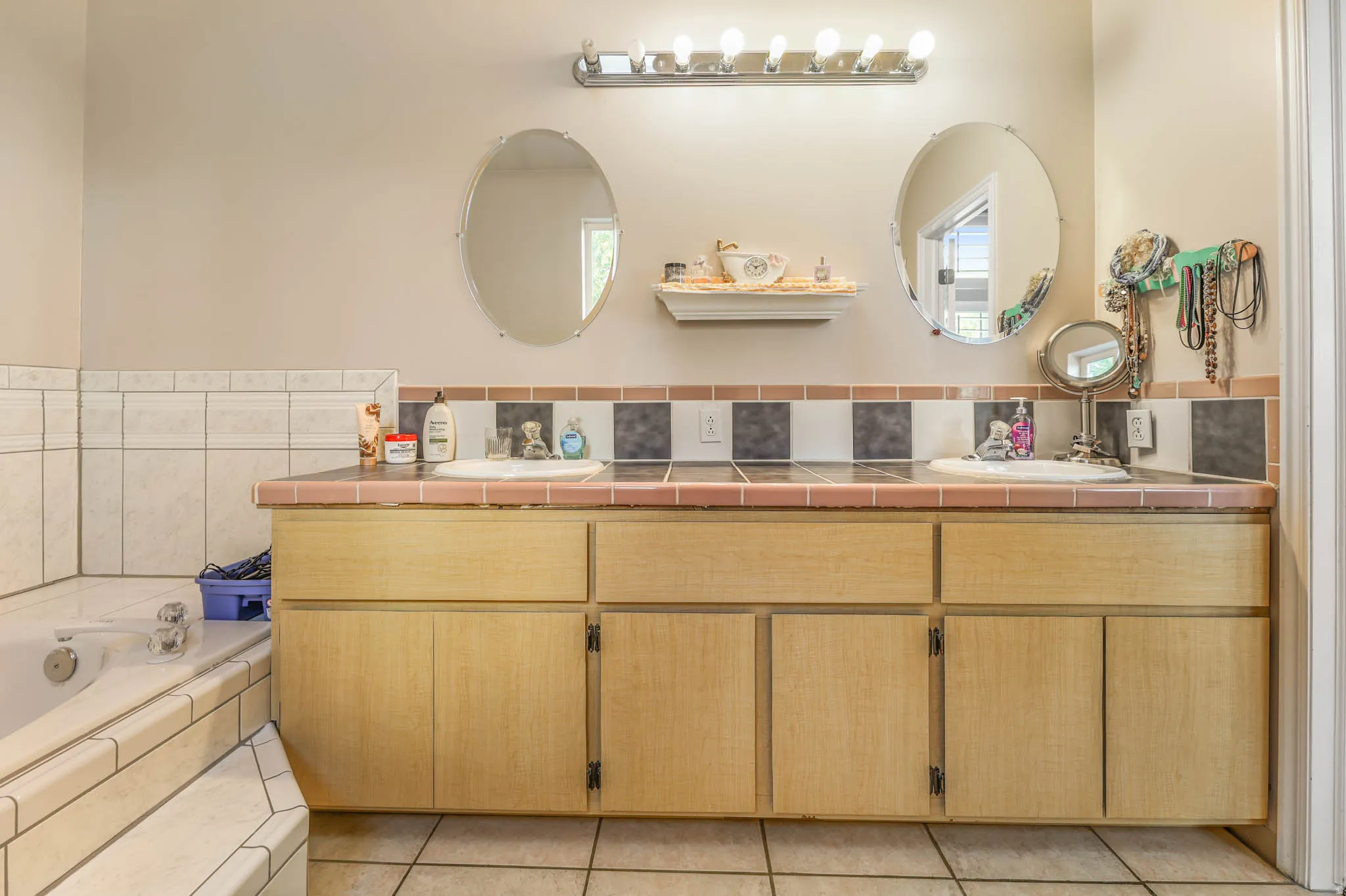 Bathroom featuring double vanity, a garden tub, and light tile patterned floors