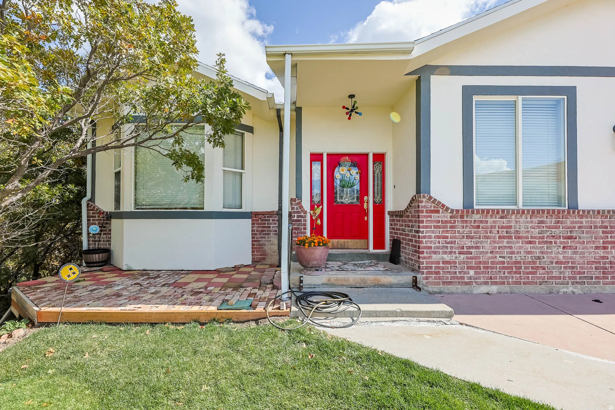 Property entrance with stucco siding, a lawn, and brick siding