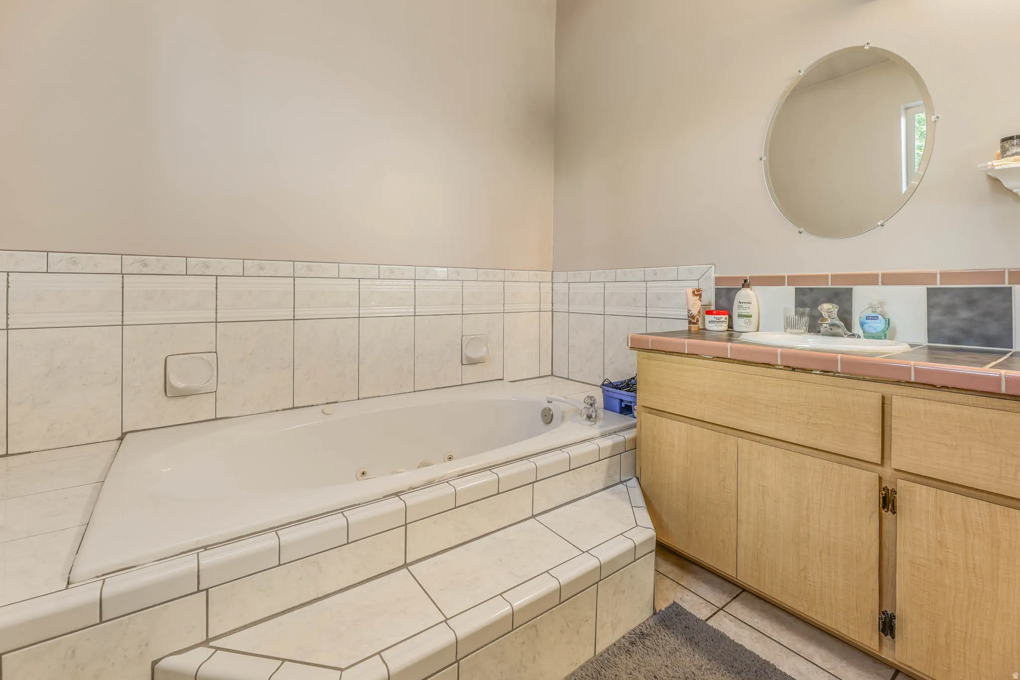 Bathroom with vanity, a whirlpool tub, and light tile patterned floors