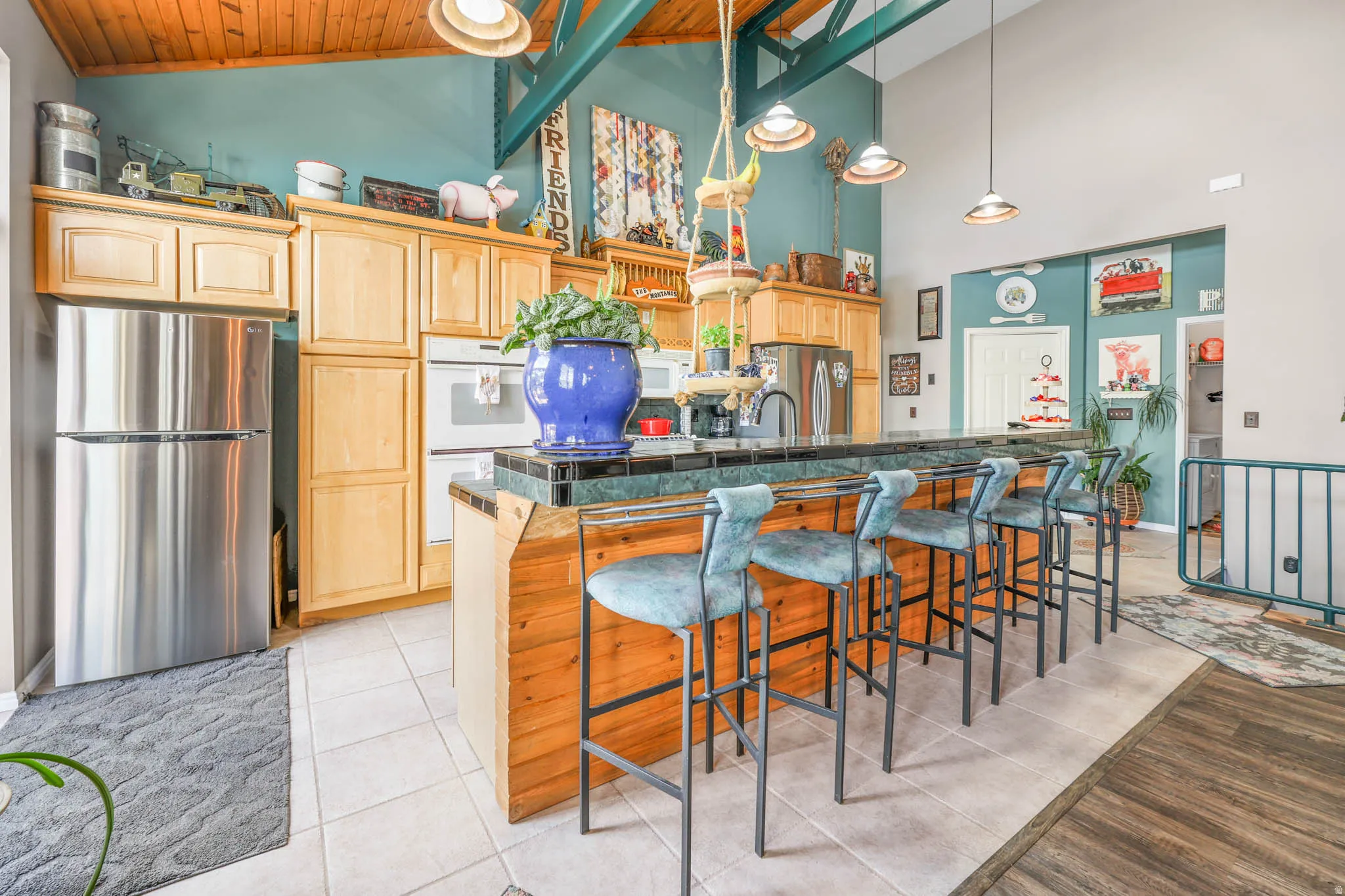 Kitchen with white appliances, lofted ceiling, dark countertops, a breakfast bar area, and light wood finish cabinets