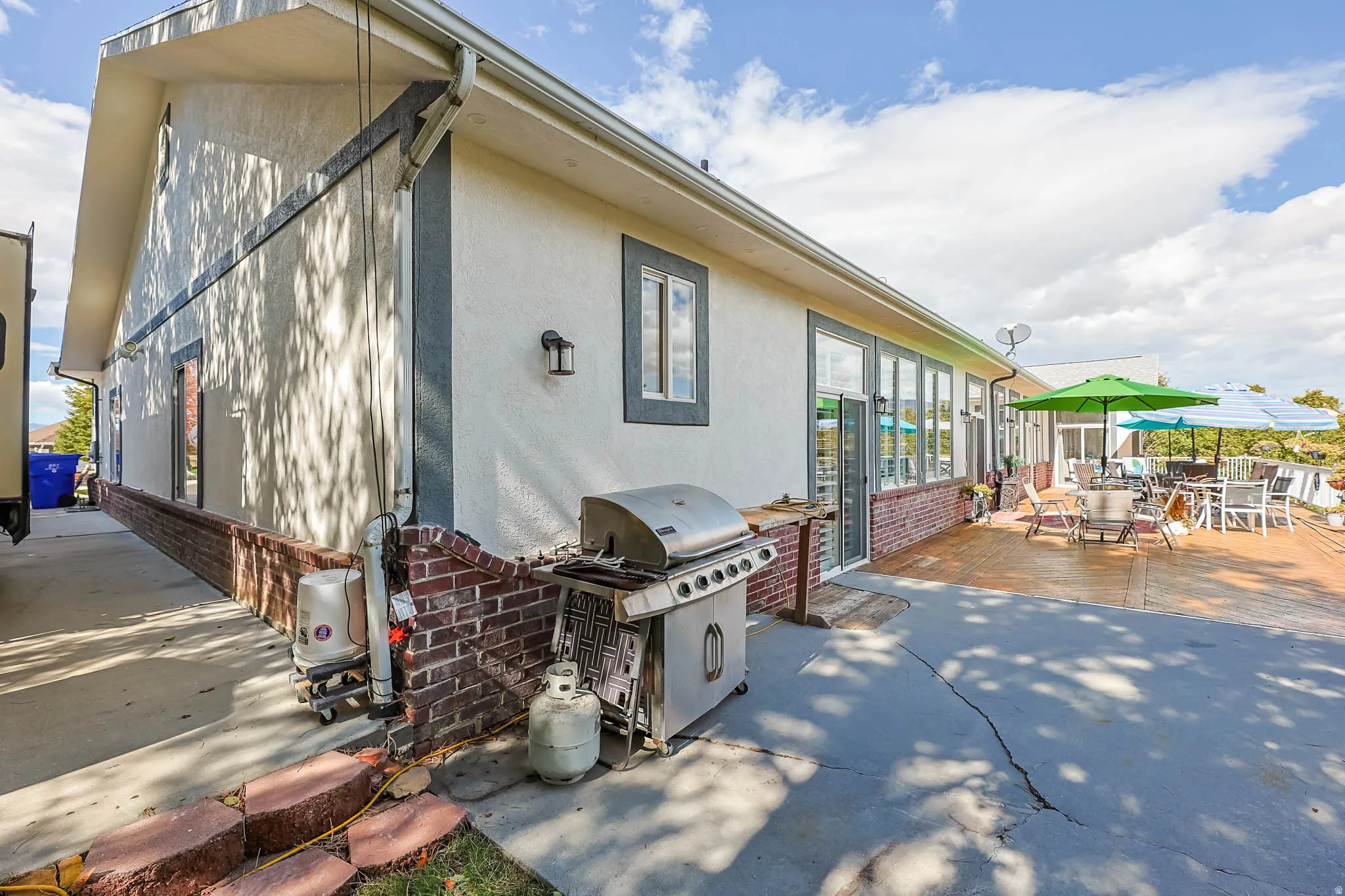 View of property exterior featuring outdoor dining area, brick siding, stucco siding, and a patio area
