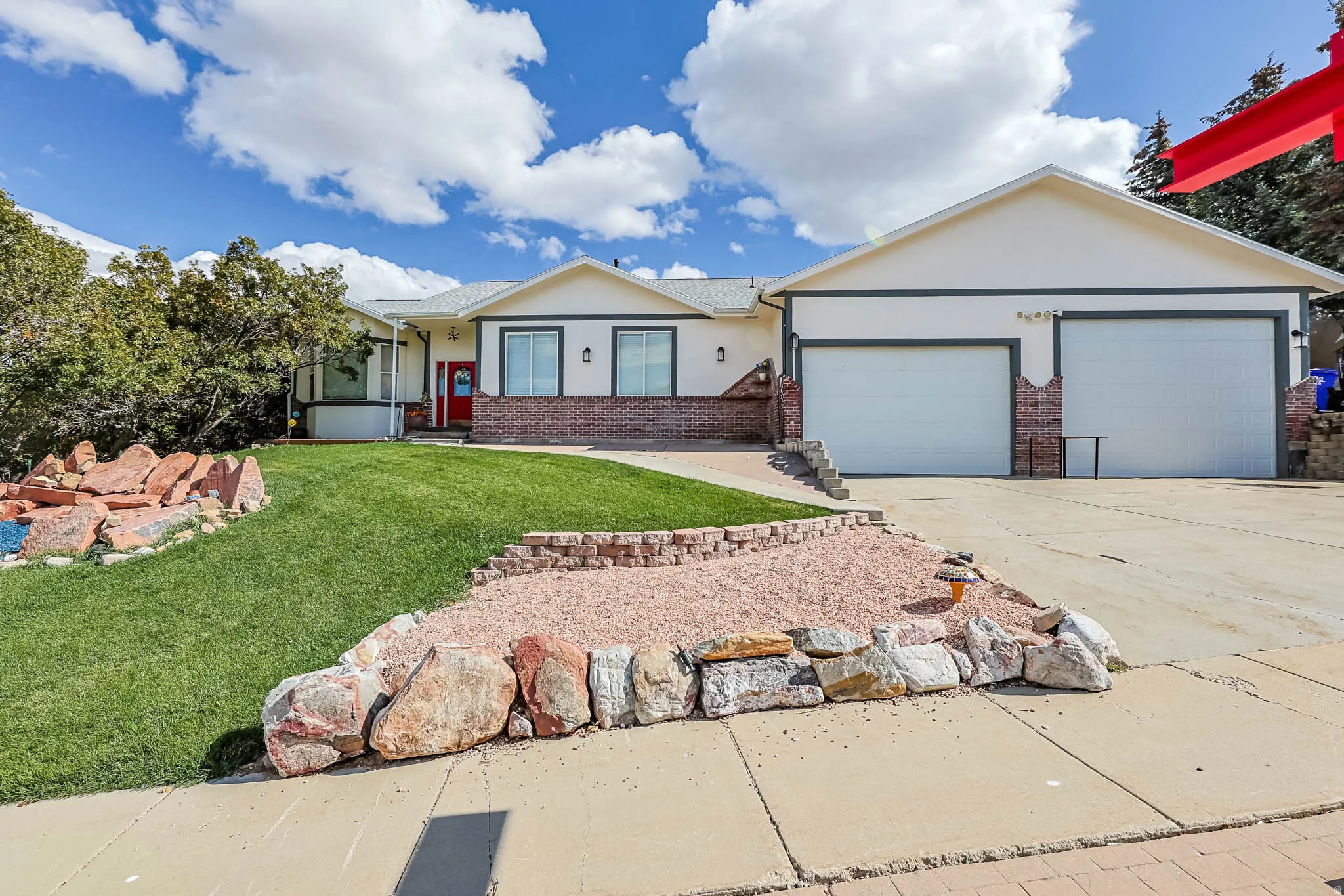Single story home with stucco siding, brick siding, a front lawn, concrete driveway, and an attached garage