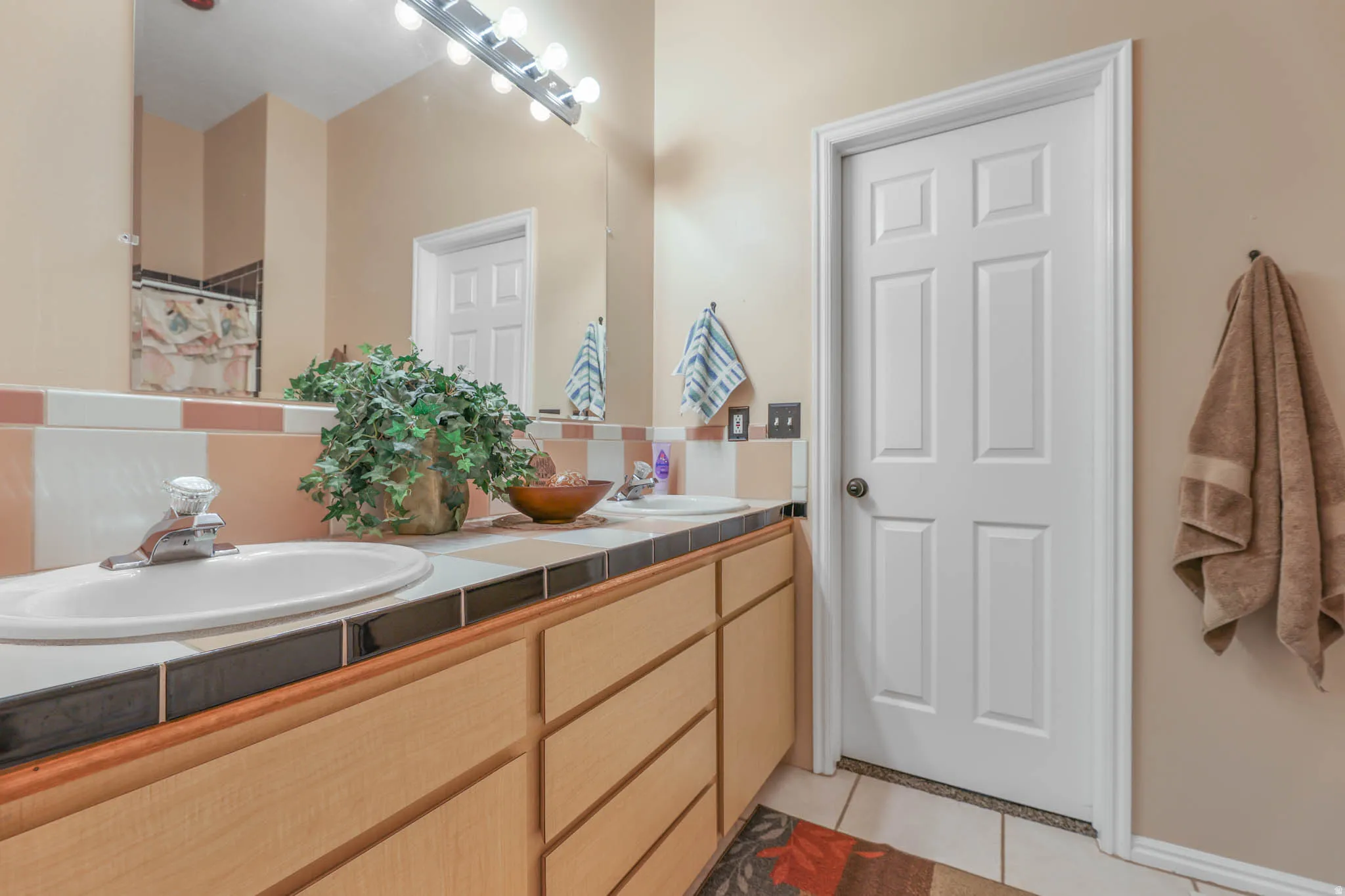 Full bath featuring curtained shower, double vanity, and light tile patterned floors