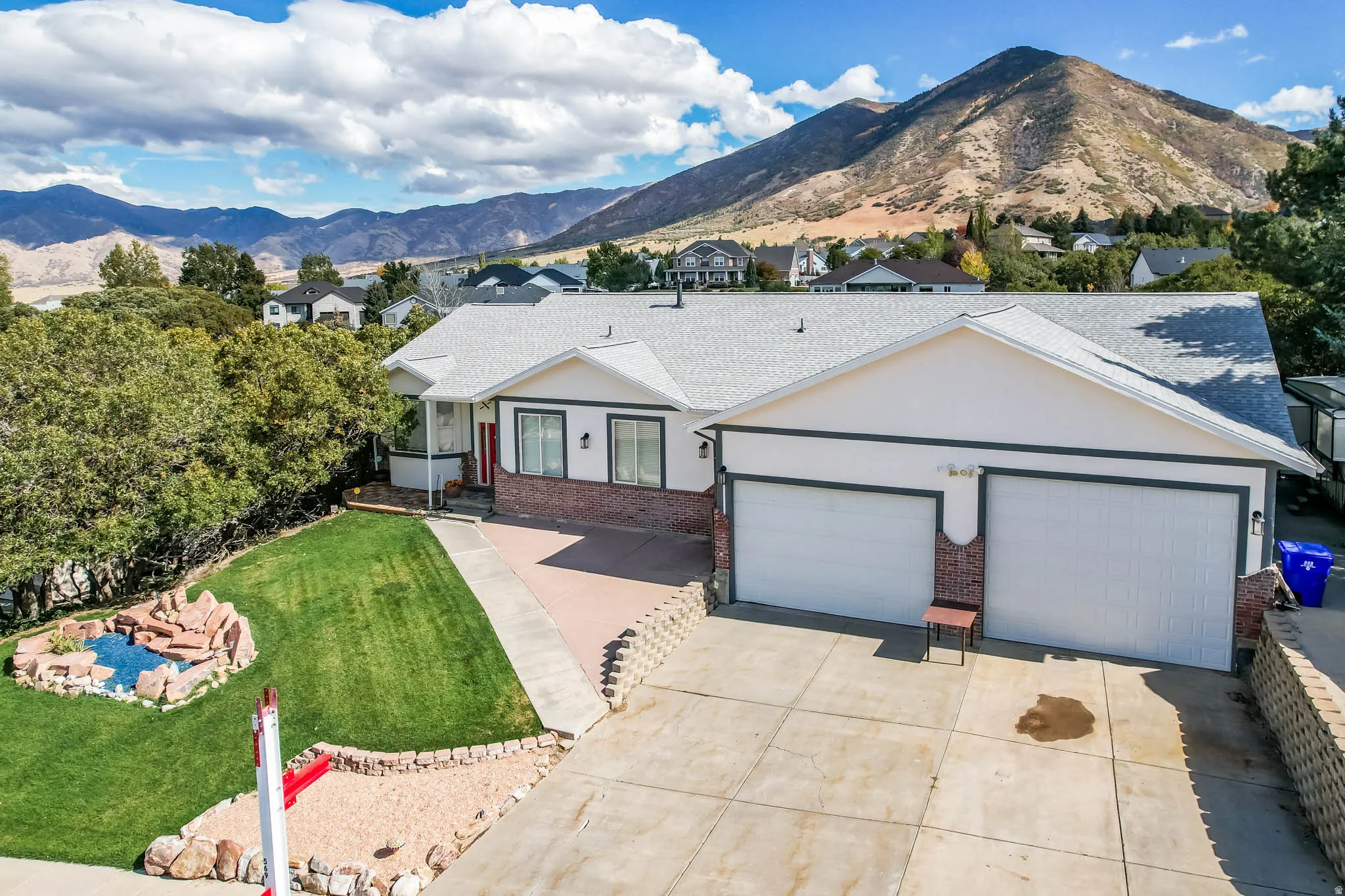 Single story home with brick siding, a mountain view, an attached garage, and driveway