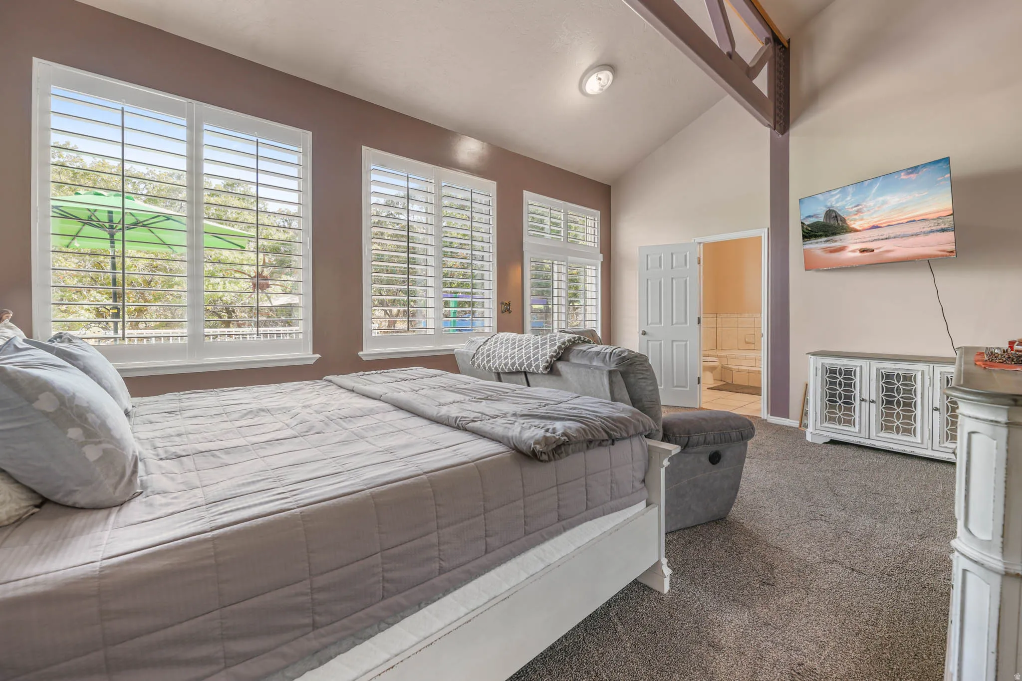 Bedroom featuring lofted ceiling, dark colored carpet, and ensuite bathroom