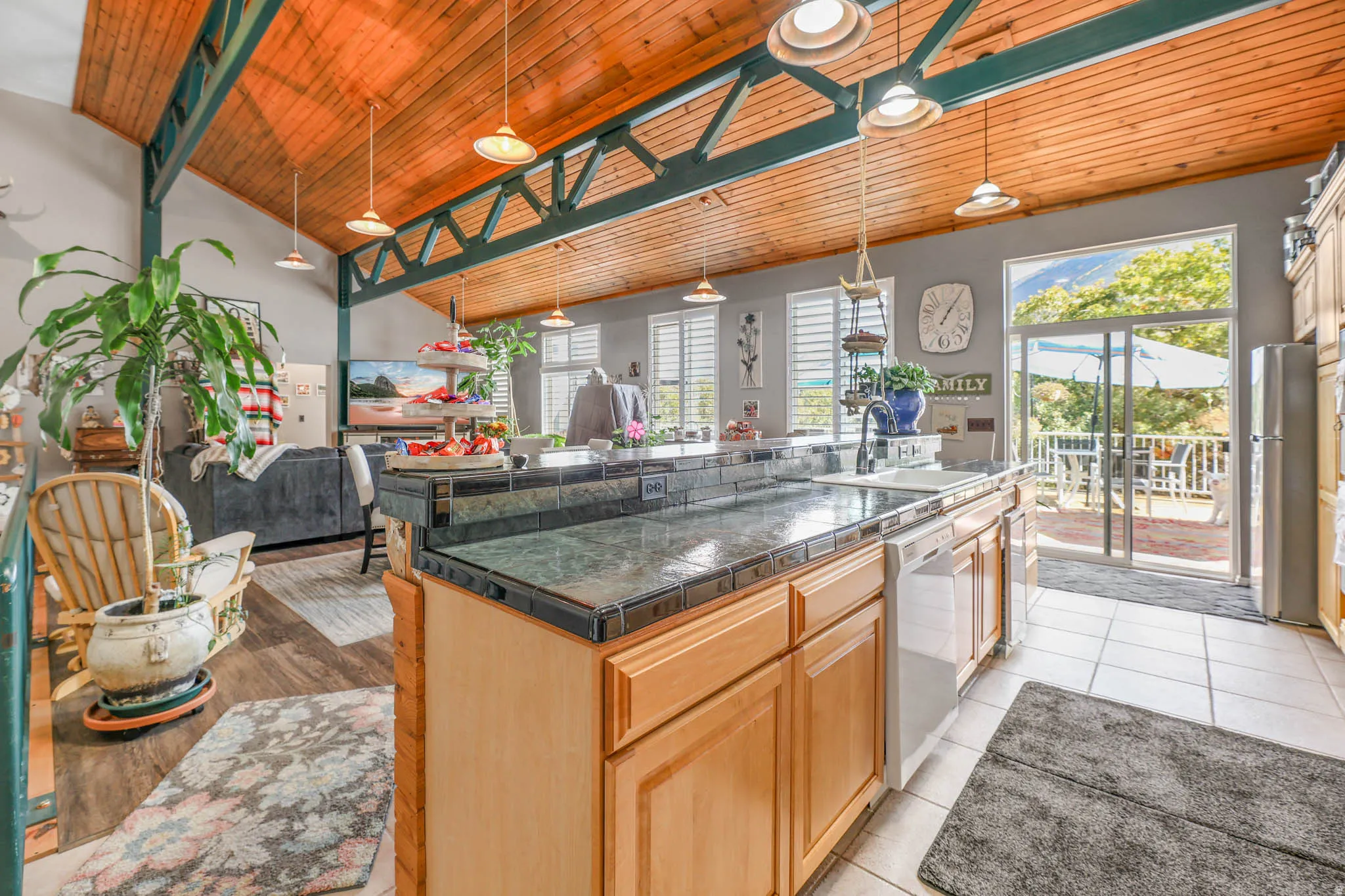 Kitchen with a center island with sink, open floor plan, a vaulted wood ceiling, dishwasher, and freestanding refrigerator