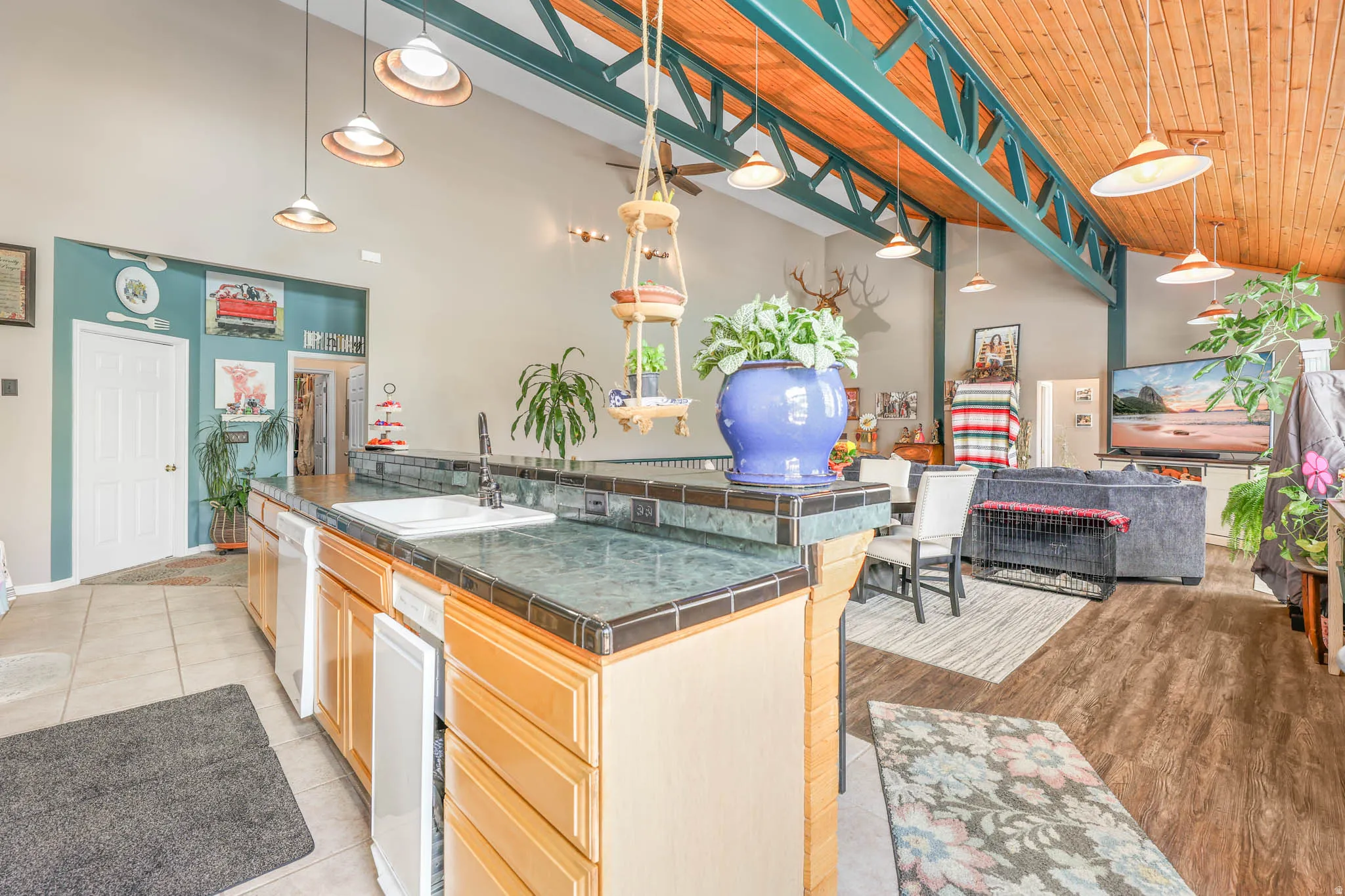 Kitchen with pendant lighting, a vaulted wooden ceiling, open floor plan, white dishwasher, and a kitchen breakfast bar