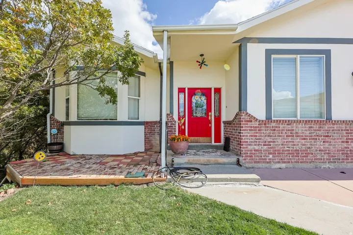 Property entrance with stucco siding, a lawn, and brick siding