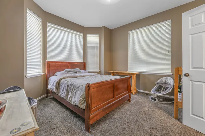 Bedroom featuring dark carpet and multiple windows