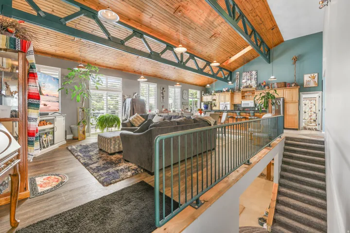 Living room with light wood-type flooring and a high wooden beamed ceiling