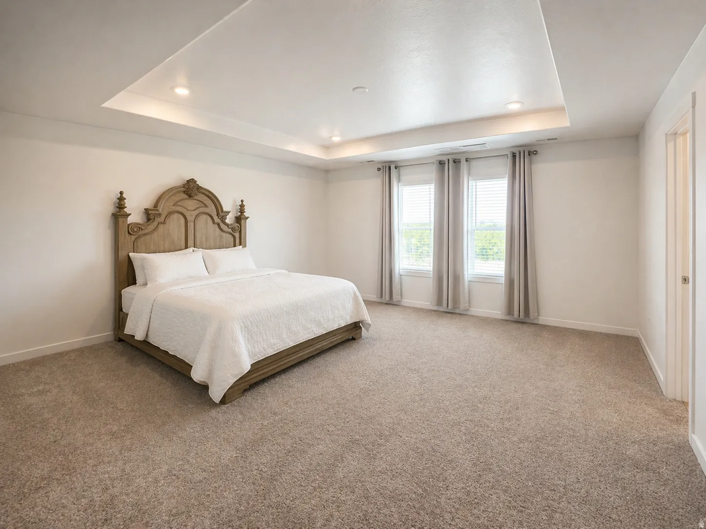 Bedroom featuring light carpet, recessed lighting, and a tray ceiling