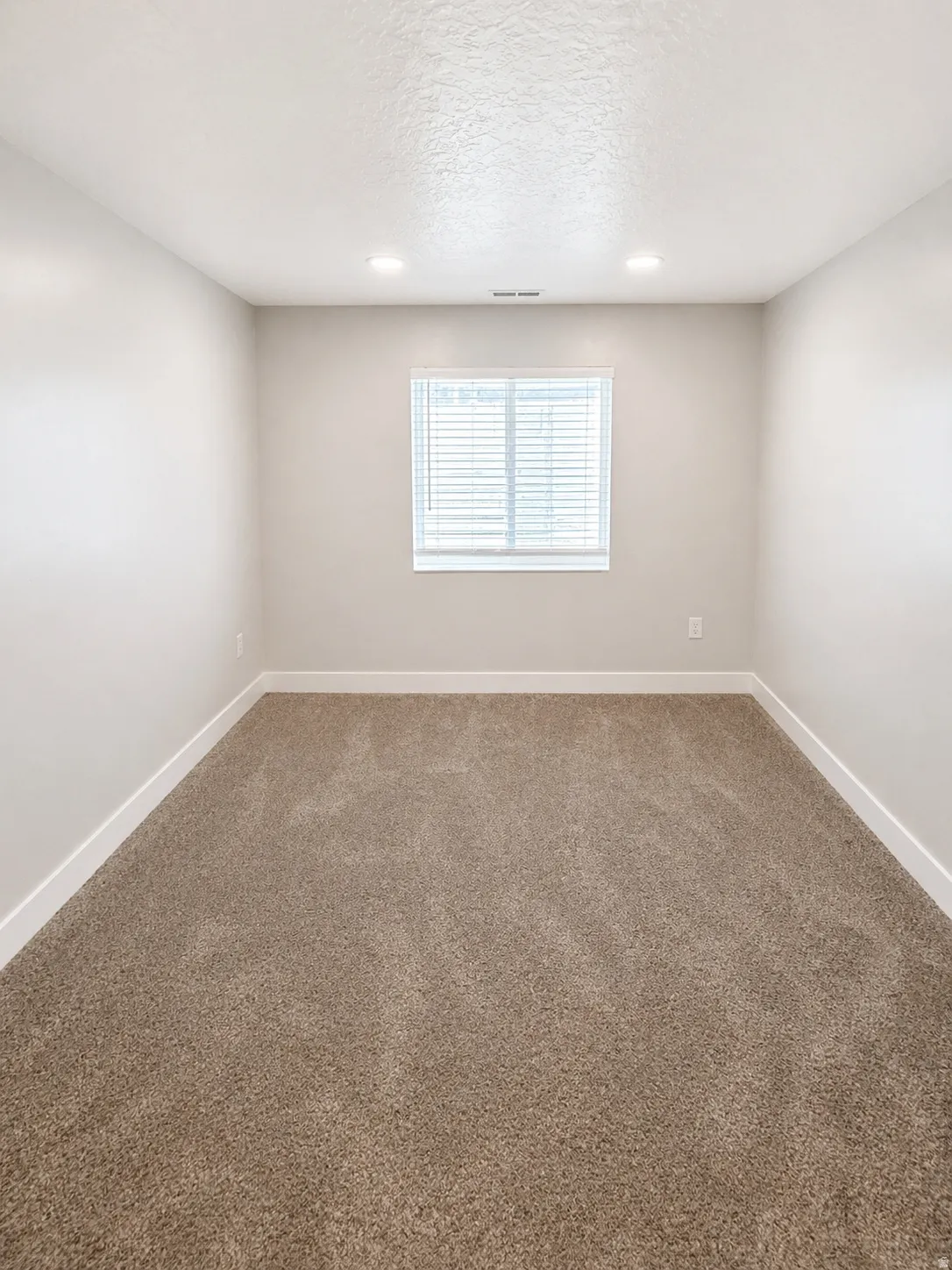 Carpeted empty room featuring a textured ceiling and recessed lighting