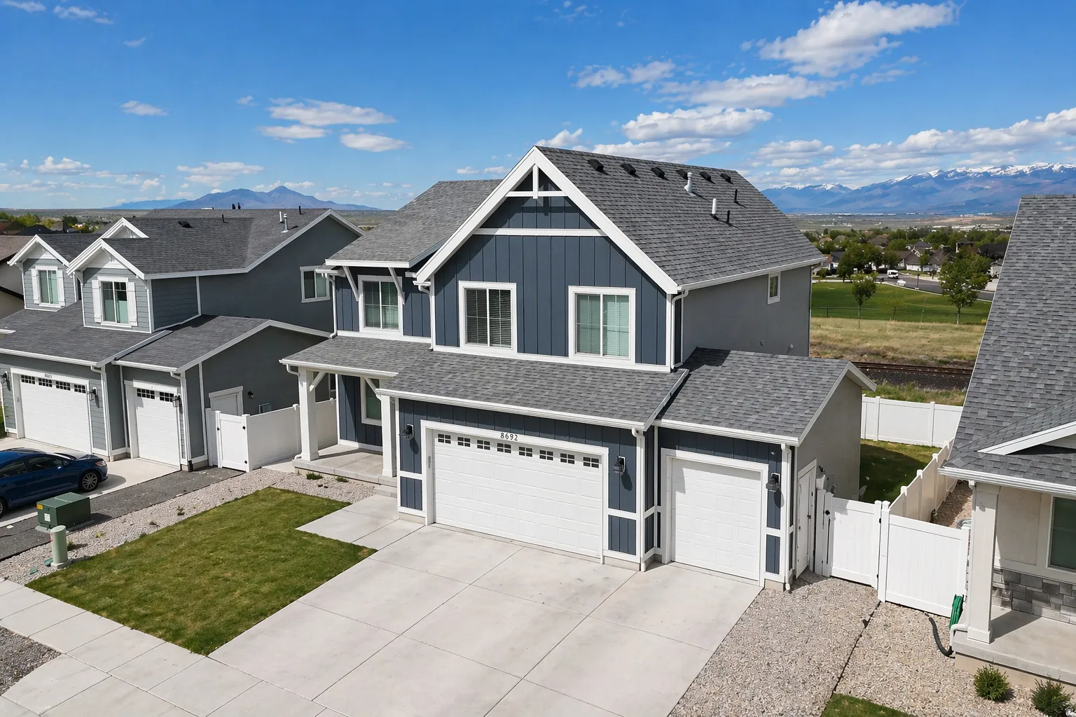 Craftsman-style home with a gate, a mountain view, board and batten siding, driveway, and roof with shingles