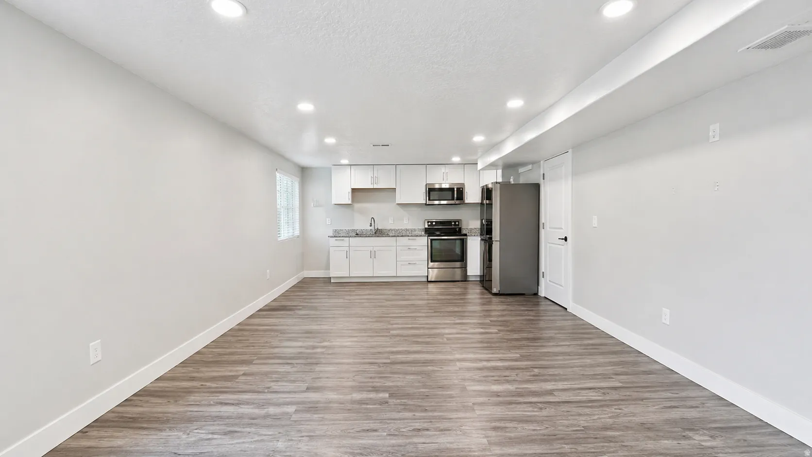 Kitchen featuring white cabinets, recessed lighting, stainless steel appliances, dark wood-style floors, and a textured ceiling