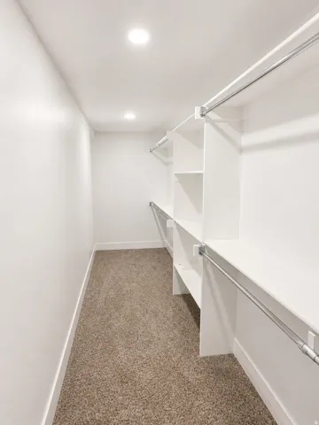 Walk in closet featuring dark colored carpet