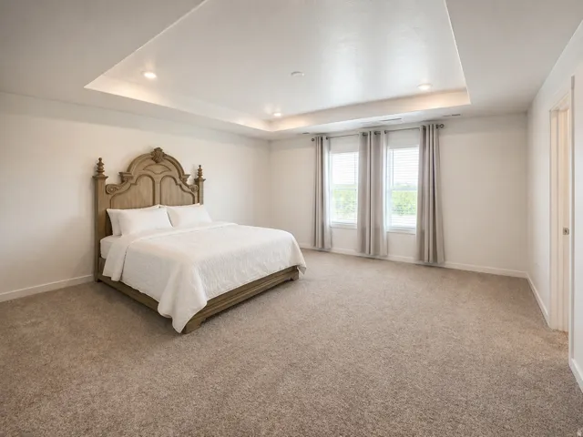 Bedroom featuring light carpet, recessed lighting, and a tray ceiling