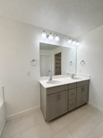Bathroom featuring double vanity, a textured ceiling, and light tile patterned flooring