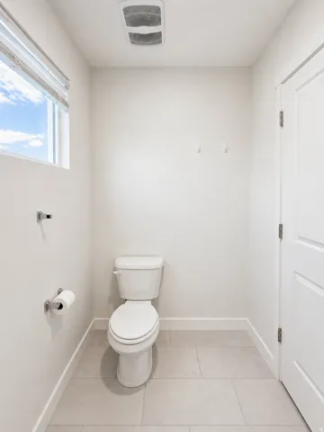 Bathroom with toilet and light tile patterned flooring