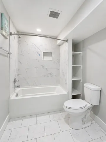 Bathroom featuring tub / shower combination and light marble finish floors