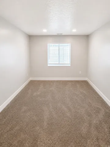 Carpeted empty room featuring a textured ceiling and recessed lighting
