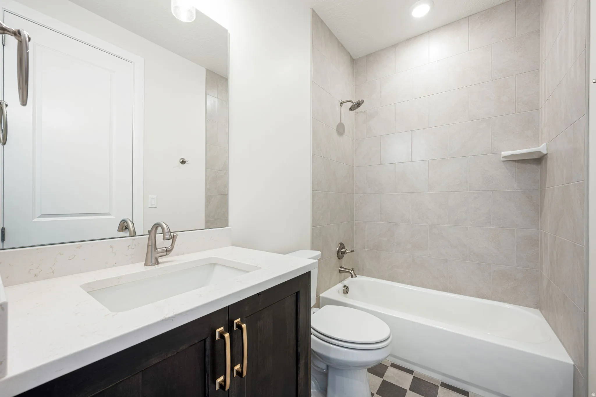 Bathroom featuring a dark wood-finish vanity with gold-tone hardware, white countertop with integrated sink, and brushed nickel faucet
