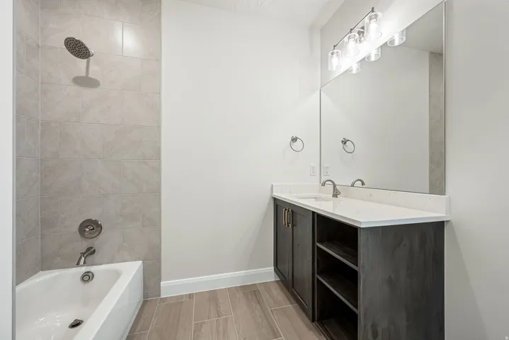 Bathroom featuring a single vanity with a white countertop, dark wood-finish cabinetry, and an integrated rectangular sink