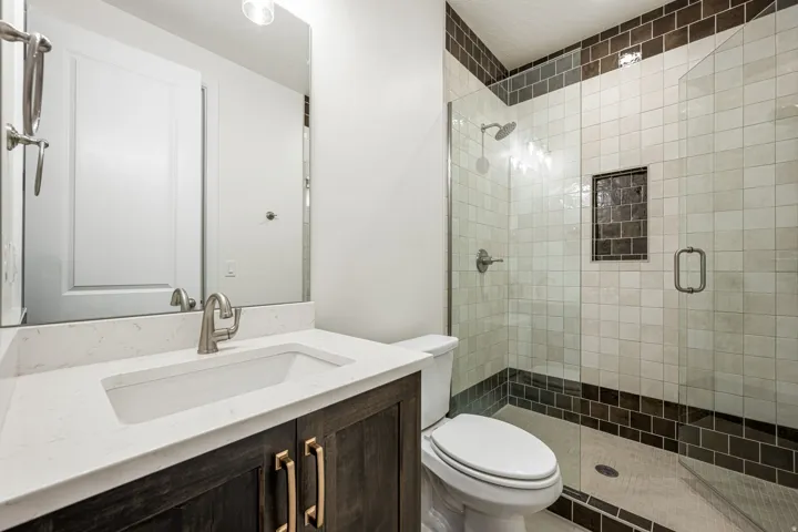 Spacious bathroom featuring a dark wood-finish vanity with gold-tone hardware, a white countertop, and an undermount sink