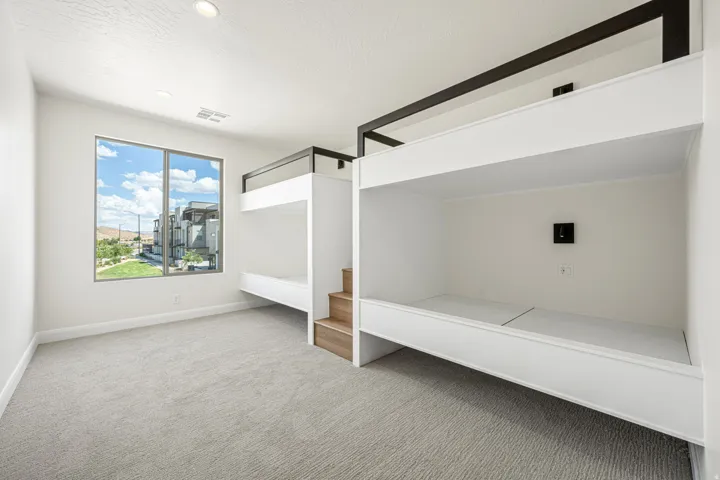 Built-in bunk beds with integrated wood-finish stairs provide efficient sleeping arrangements