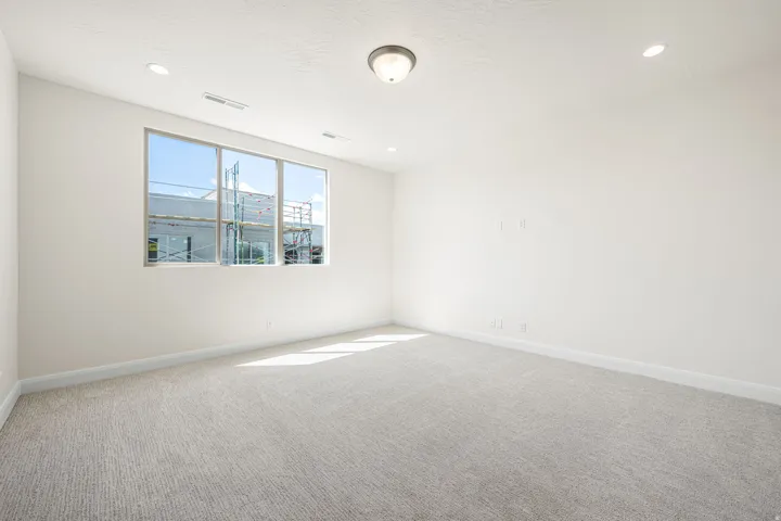 Bright room featuring a three-panel window, light textured carpet, recessed lighting, and a flush-mount ceiling fixture