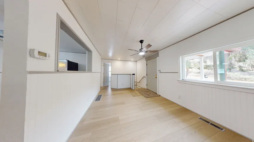 Spacious room featuring wood-finish flooring, white paneled walls, and a recessed pass-through window
