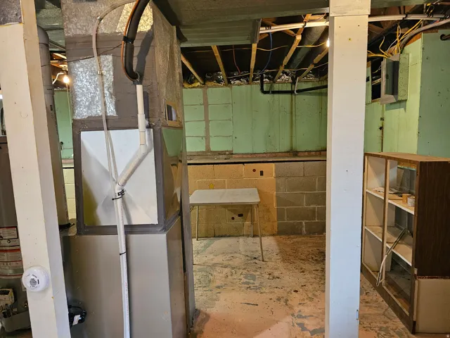 Unfinished basement featuring heating unit and water heater