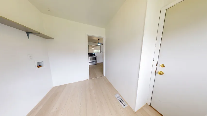Interior space with light wood-finish flooring, white walls, and a built-in shelf