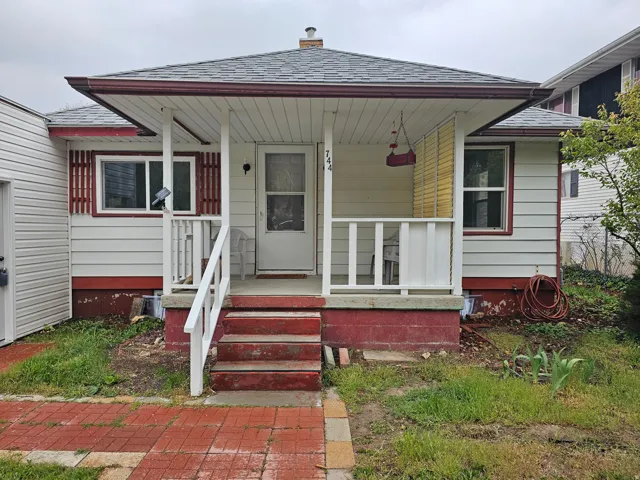 Entrance to property with covered porch, roof with shingles, and a chimney