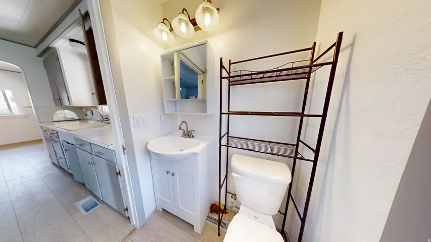 Bathroom with a corner vanity sink, wall-mounted medicine cabinet, and a two-bulb vanity light fixture