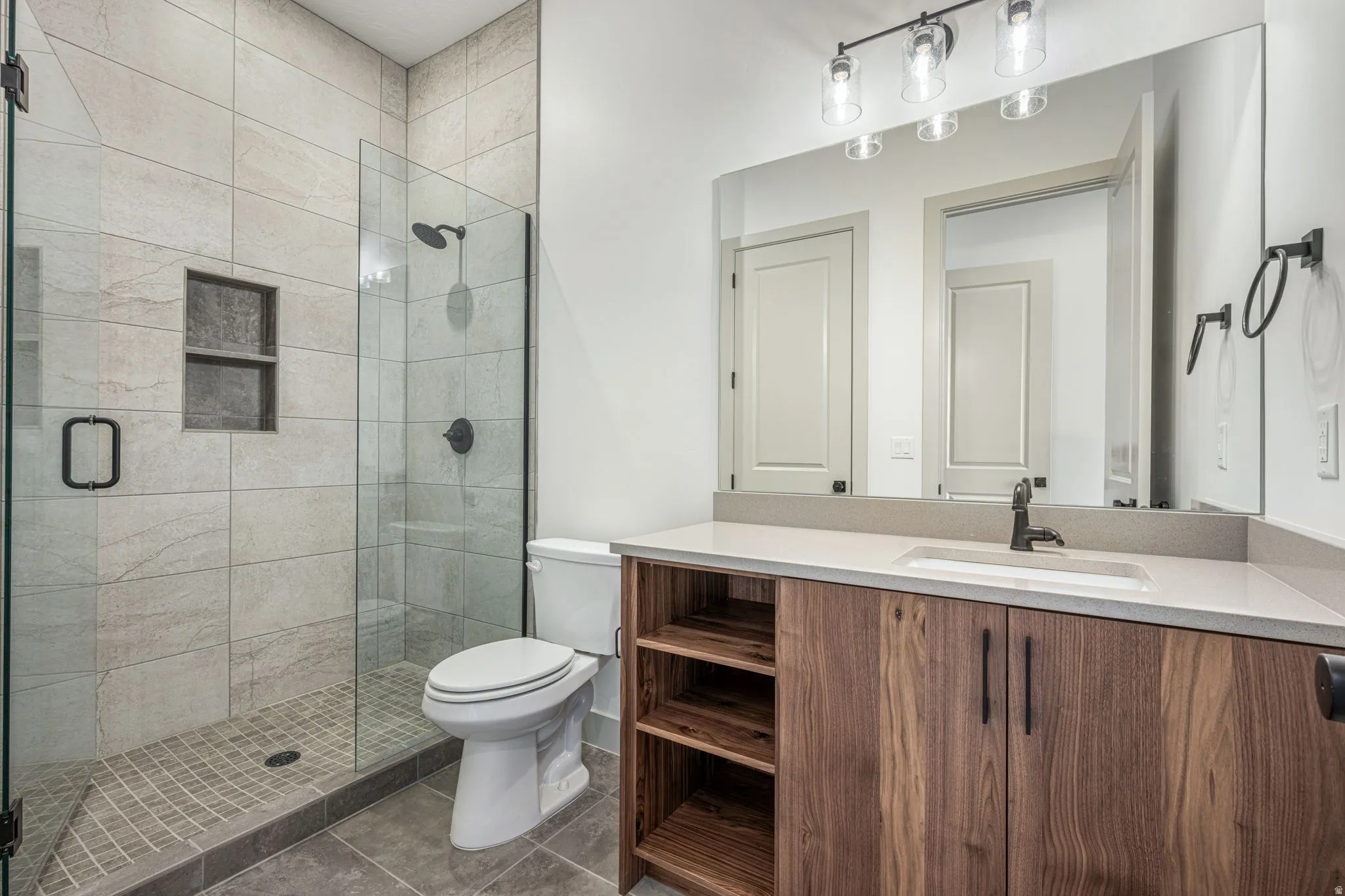 Bathroom featuring a glass-enclosed shower with tiled walls and an integrated niche