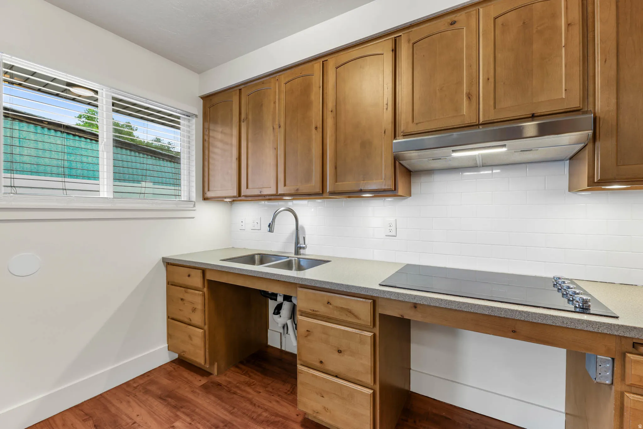 UNIT #2 Kitchen with black electric stovetop, backsplash, light stone countertops, dark wood-style floors, and wood finish cabinetry