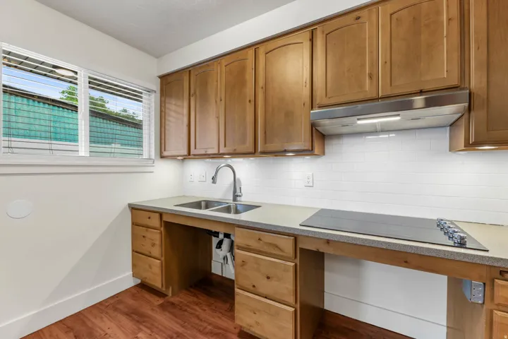 UNIT #2 Kitchen with black electric stovetop, backsplash, light stone countertops, dark wood-style floors, and wood finish cabinetry
