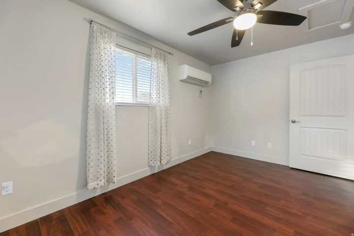 UNIT #1 Empty room with a ceiling fan and dark wood-style flooring