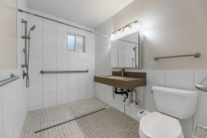 UNIT #2 Bathroom with tile walls, pet washing station, a tile shower, and a wainscoted wall