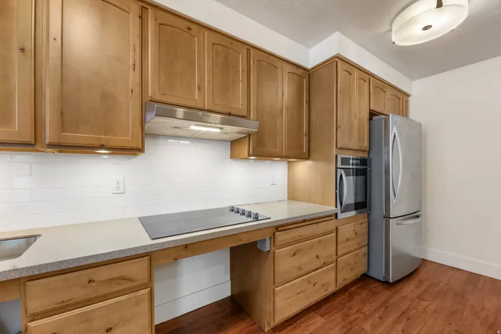 UNIT #2 Kitchen featuring stainless steel appliances, light stone countertops, backsplash, and dark wood finished floors