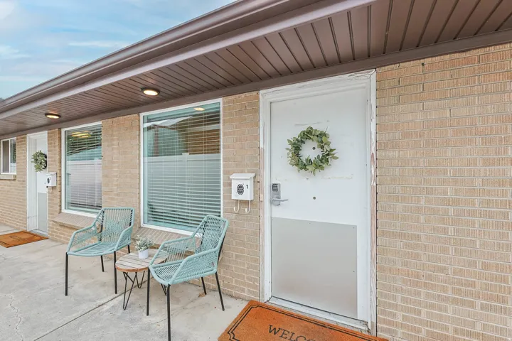 UNIT #1 View of exterior entry featuring brick siding and a porch
