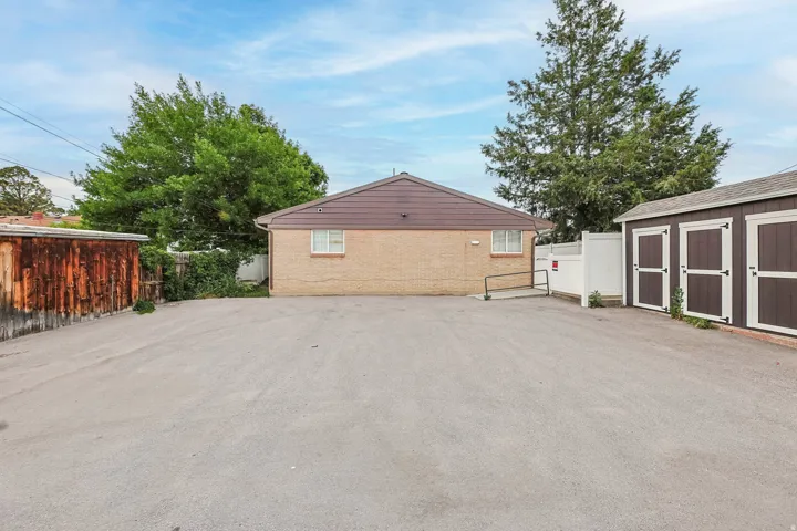 View of property exterior with brick siding and a storage unit