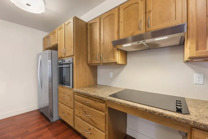 UNIT #1 Kitchen featuring stainless steel appliances, light stone counters, dark wood finished floors, wood finish cabinetry, and built in study area