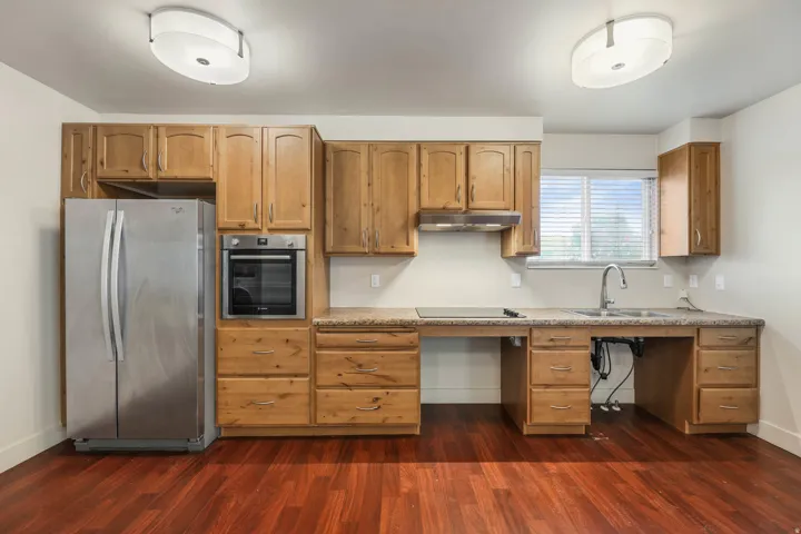UNIT #1 Kitchen featuring stainless steel appliances, dark wood-type flooring, wood finish cabinets, and light stone counters