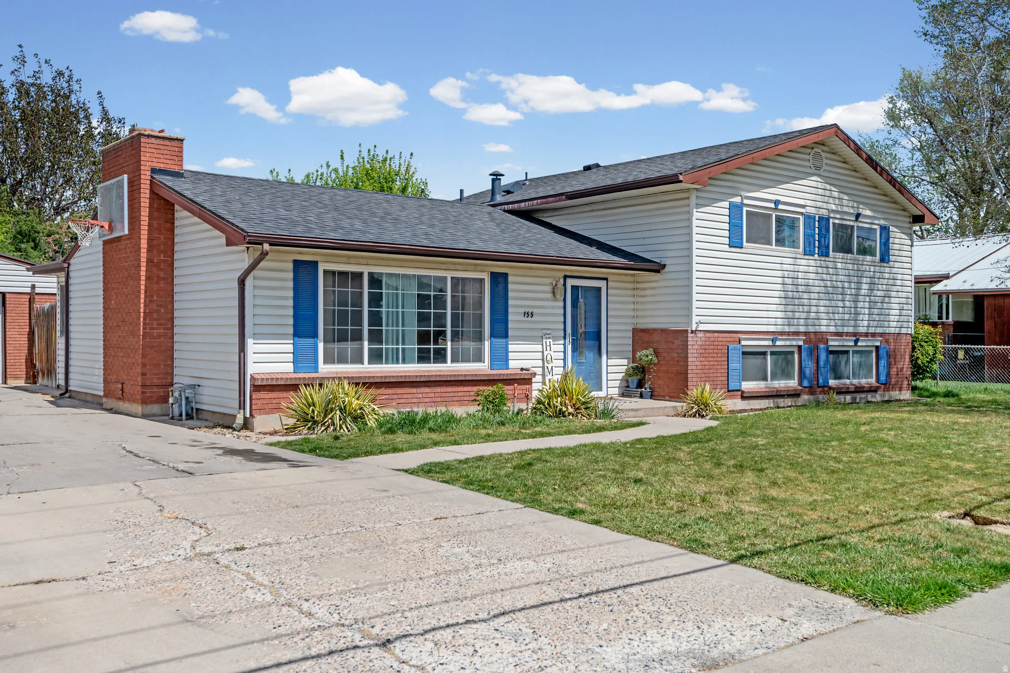 Split level home featuring roof with shingles, brick siding, and a chimney