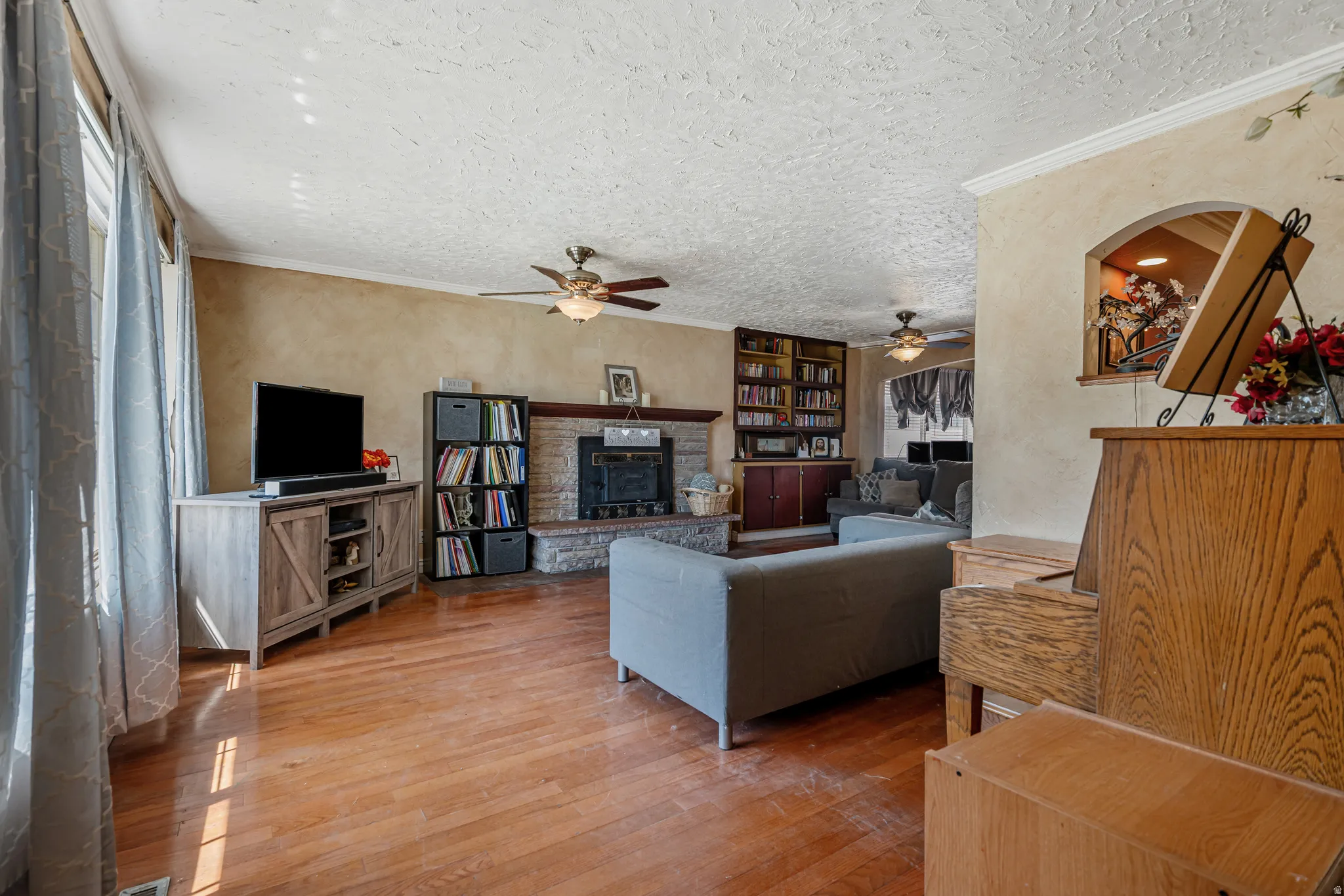 Living room featuring hardwood / wood-style flooring, a textured ceiling, crown molding, and a textured wall